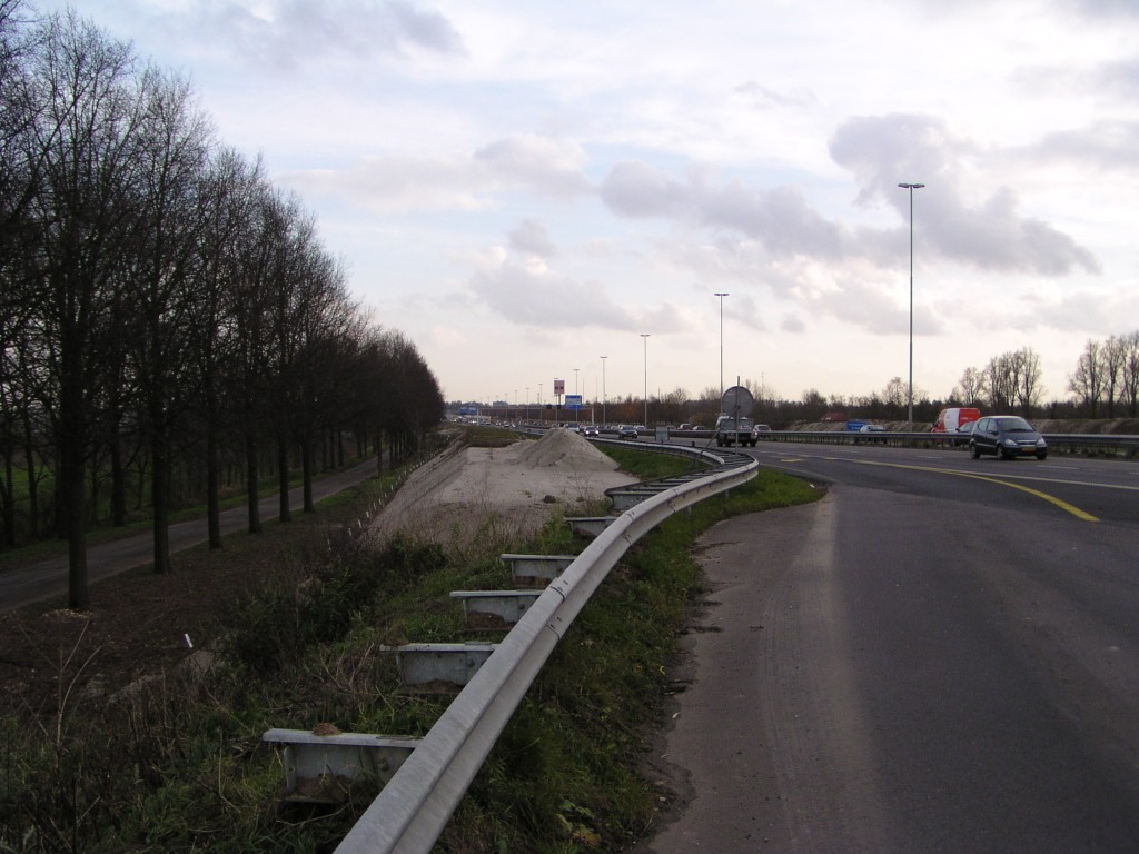 p1010017.jpg - Foto genomen vanaf de speciaal aangelegde werkverkeer afrit ter ontsluiting van de tijdelijke haven voor zandschepen uit de vorige foto, vlak voor de Maasbrug. "Einde werk" staat er op de TB tekening, het wordt het voorlopig einde van 2x3 vanaf den Bosch in de richting Zaltbommel. Het nieuwe zandlichaam links is nodig voor die 2x3.