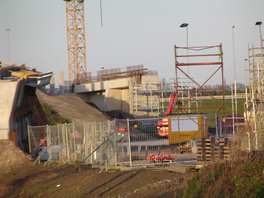 p1010039.jpg - Poging om het forse landhoofd voor het oostelijk deel van de flyover A58 west->oost in beeld te brengen. De camera vondt het bouwhek echter geschikter om op scherp te stellen.