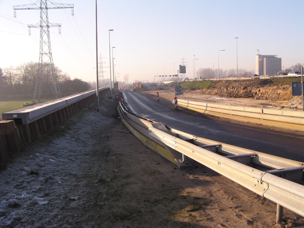 pc220023.jpg - Let u even niet op het wegdek tussen de barriers, dat is tijdelijk. Het gedeelte achter de naad in het asfalt van de toerit N69->A67 richting Venlo is permanent, en hier kan men mooi zien hoe extra golfbaan hobbels ontstaan op de toeritten. Immers, de toerit moet stijgen om het hoogteniveau van de parallelbaan te halen, maar daalt daarna meteen weer omdat de parallelbaan daalt tussen de aansluitingen. Dit effect is nog sterker op de toerit Veldhoven zuid richting het zuiden, omdat die toerit een stuk korter is.