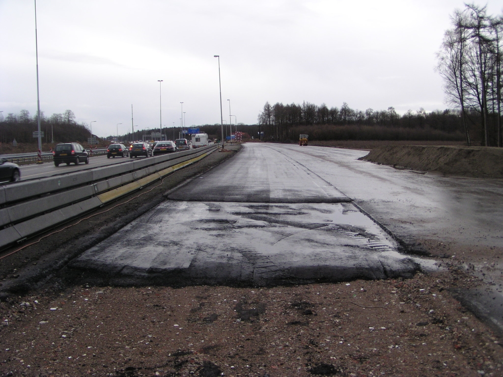 p1050002.jpg - De ruimte tussen de parallelbaan west vanaf de aansluiting Airport naar het zuiden is hier opgevuld met asfalt, dat aan de linker kant strak tegen de bestaande hoofdrijbaan aanligt (zie ook  hier ). Ik gok er dan ook op dat hier het eerste stukje parallelbaan in gebruik genomen gaat worden, waarbij het verkeer een slinger gaat maken komende vanaf de hoofdrijbaan, over dit tijdelijke overbuggingsasfalt, naar de parallelbaan.