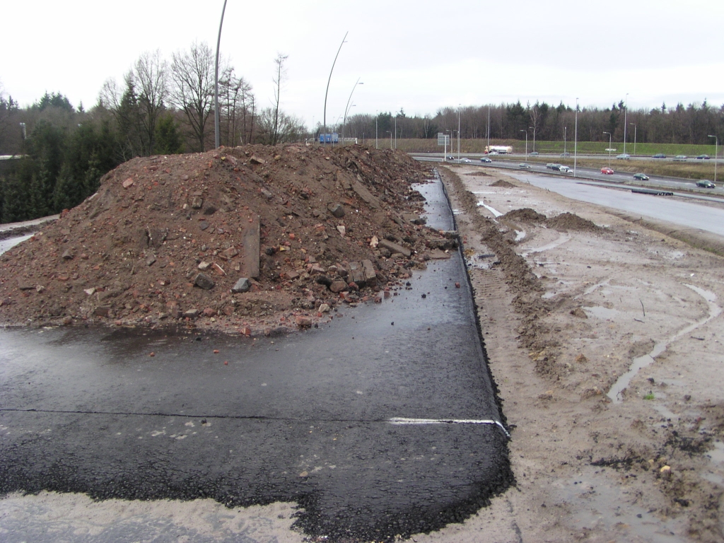 p1050005.jpg - Bovenaan het talud voor de afrit Strijp/Centrum is een hoeveelheid puin gestort. In het puin bevinden zich onder meer kinderhoofd straatklinkers, zodat het best kan zijn dat de gedeeltelijk geamoveerde Vensedijk een tweede leven gaat krijgen als bijvoorbeeld opvulmateriaal voor het betonnen landhoofd uit de vorige foto.