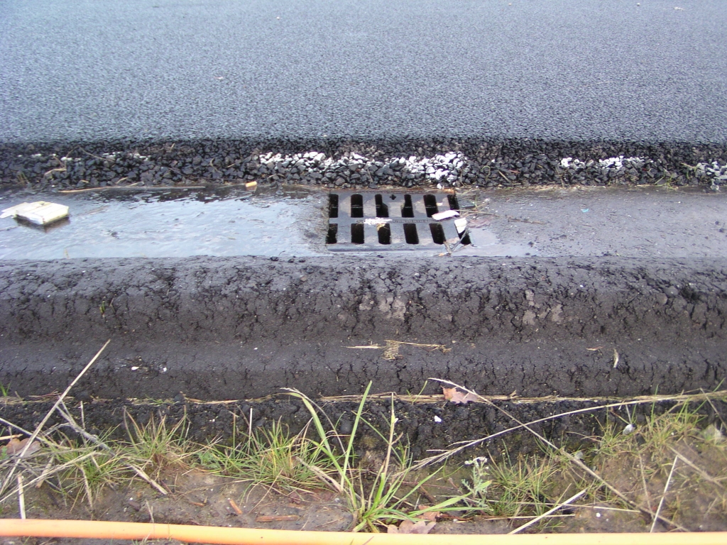 p1050017.jpg - Ook in zijaanzicht zijn de twee ZOAB lagen van verschillende korrel nog te onderscheiden. De goot ten behoeve van hemelwater afvoer is geintegreerd in het asfalt.