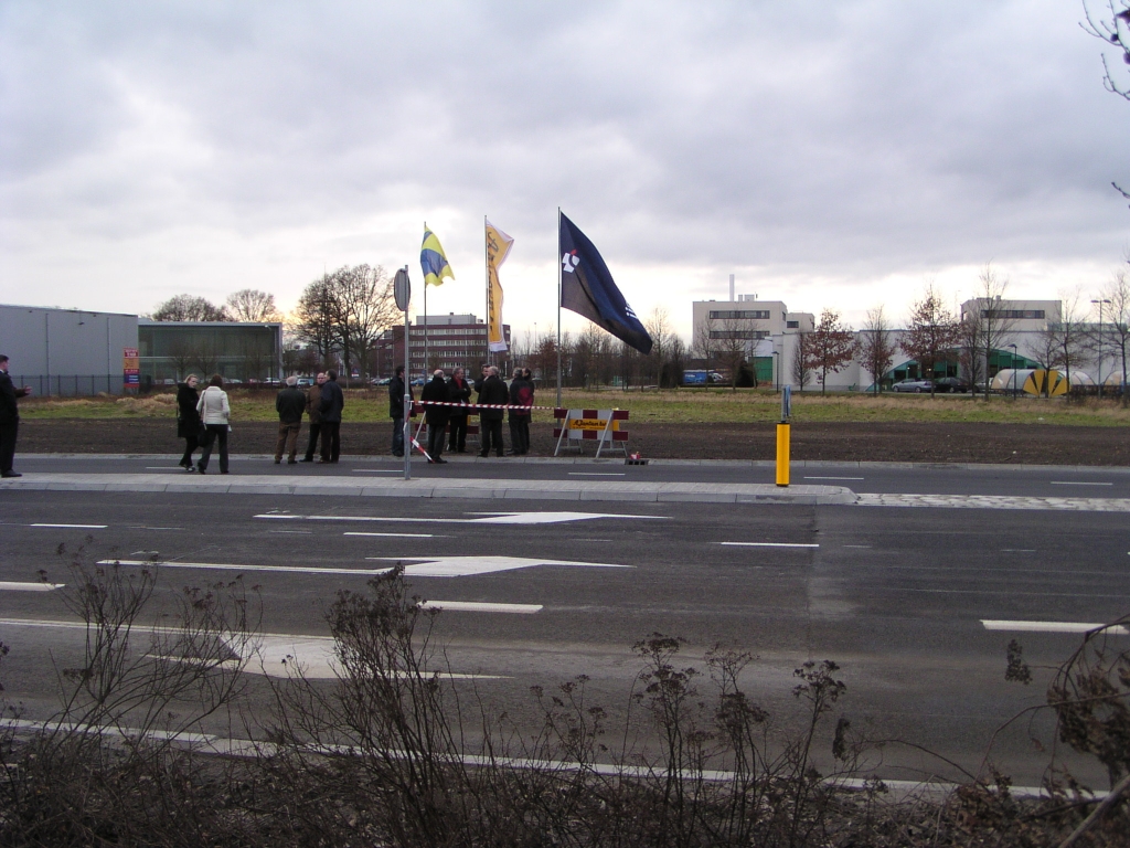 p1160002.jpg - Op het nieuwe OWN op bedrijventerrein Ekkersrijt, aangelegd ten behoeve van de nieuwe aansluiting op de A50/A58, is een groepje notabelen bijeengekomen voor de officiele opening. Het lint staat strak gespannen.