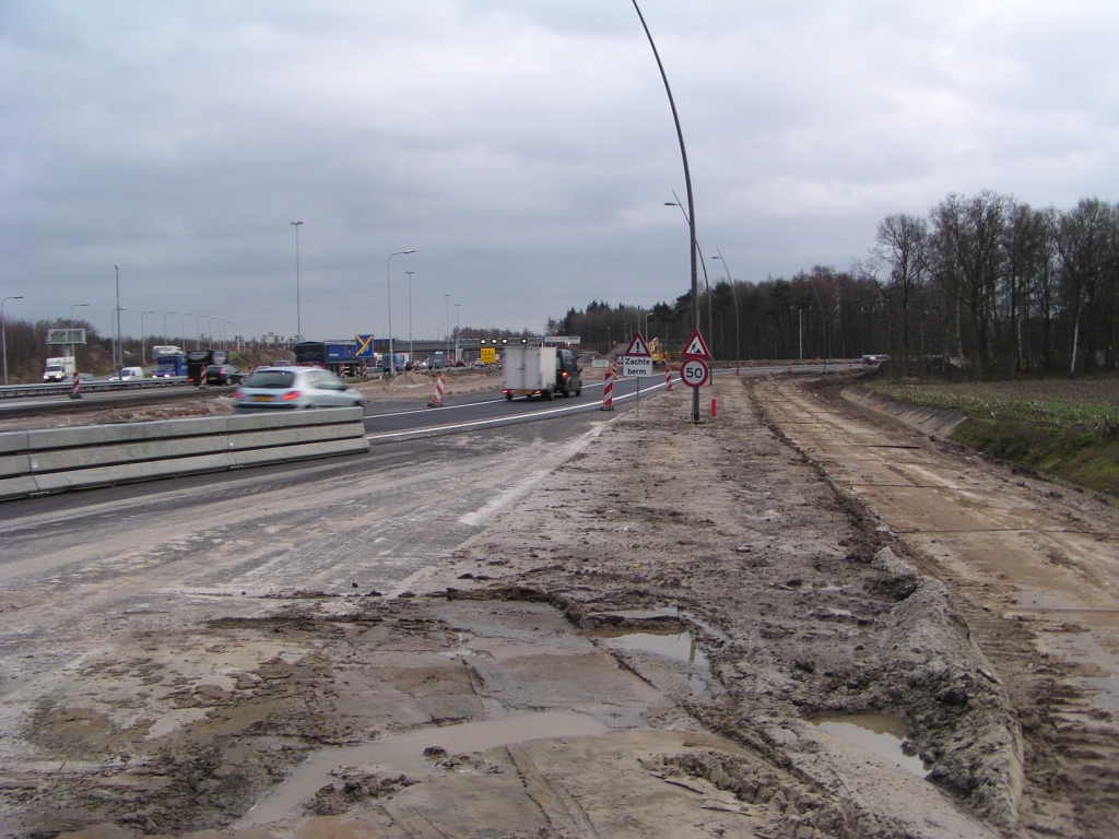 p1250016.jpg - Even om het hoekje van de barriere kijken van de vernieuwde afrit Airport vanuit de richting Amsterdam. Zoals op andere plekken in het project is de tijdelijke overgang over de parallelbaan met een dun toplaagje uitgevoerd. Overigens is heel de afrit tot aan de Anthony Fokkerweg vernieuwd inclusief vergroting van het aantal opstelstroken bij de VRI bovenaan. Ook de lichtmasten zijn vervangen door het nieuwe gebogen model. Een knap staaltje werk voor 1 weekend.