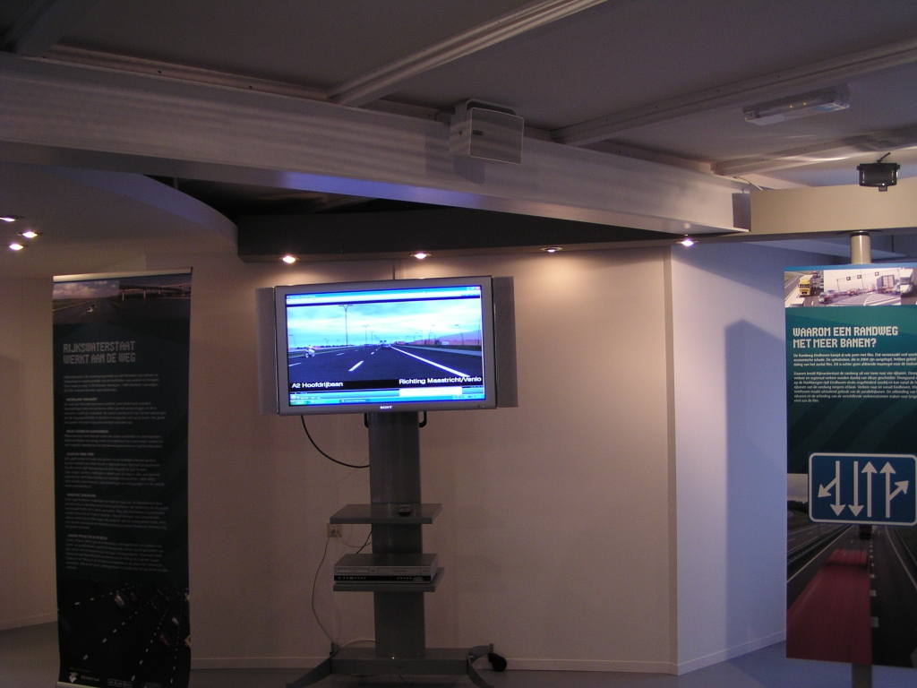 p1290006.jpg - Uit het  Eindhovens Dagblad :  In de nieuwe productie, die op een levensgroot scherm wordt vertoond, is te zien hoe de randweg er vanaf 2010 uit gaat zien.  Dit is het levensgrote scherm in het Informatiecentrum in Veldhoven.