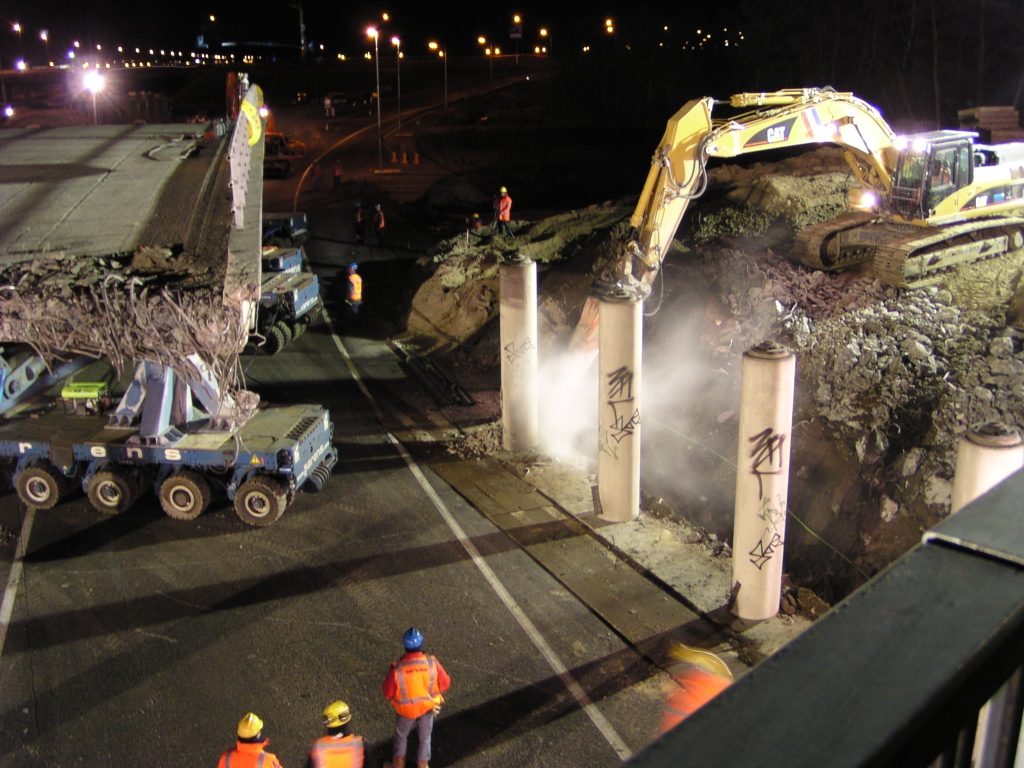 p2160025.jpg - Vermoedelijk is men koortsachtig bezig de achterste platform carrier, die het viaduct heeft doen breken, weer op orde te brengen, waardoor de uitvaartstoet lange tijd stil staat. Het slopen van de pilaren gaat gewoon door.