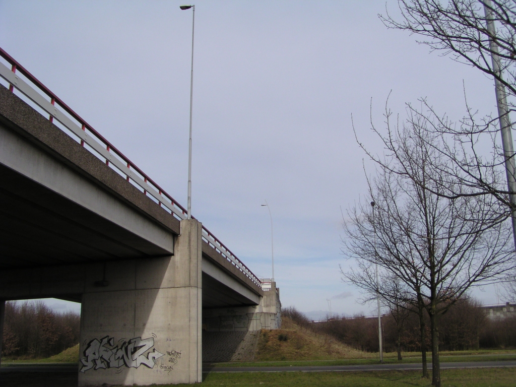 p3020065.jpg - In Kp. Ekkerswijer, dat buiten het projectgebied valt, is men bezig lichtmasten te upgraden naar de nieuwe modellen die ook overal langs de nieuwe randweg komen te staan. Hier op de A58 zien we het lichtgebogen model "hoofdrijbaan" staan, met op de voorgrond nog een oud model.