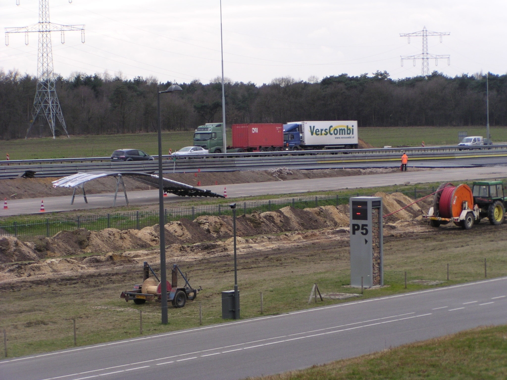 p3070011.jpg - Voorbereidende activiteiten voor het plaatsen van lichtmasten, die reeds gereed liggen. Op de voorgrond een project dat losstaat van de Randweg: het ingraven van een 10 kV leiding van het trafostation aan de Genneperweg naar een nieuwe ASML fabriek in Veldhoven.