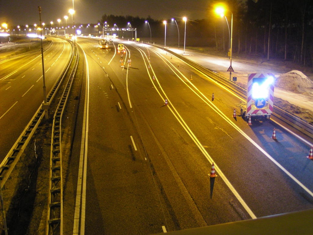 p3160022.jpg - Aan de noordzijde van het viaduct is, netjes volgens planning, iets na 02:00 de politiestop actief. Openstelling van de parallelbaan is vooralsnog enkelstrooks, gemarkeerd met pionnen. Ook de invoeger vanaf Airport is met pionnen afgezet. In de stilte die nu heerst kan men het ijzerdraad (?) horen dat door personeel met ruimtelijk inzicht wordt gepositioneerd op de rijbaan om de nog ontbrekende markering aan te duiden met witte stippen.