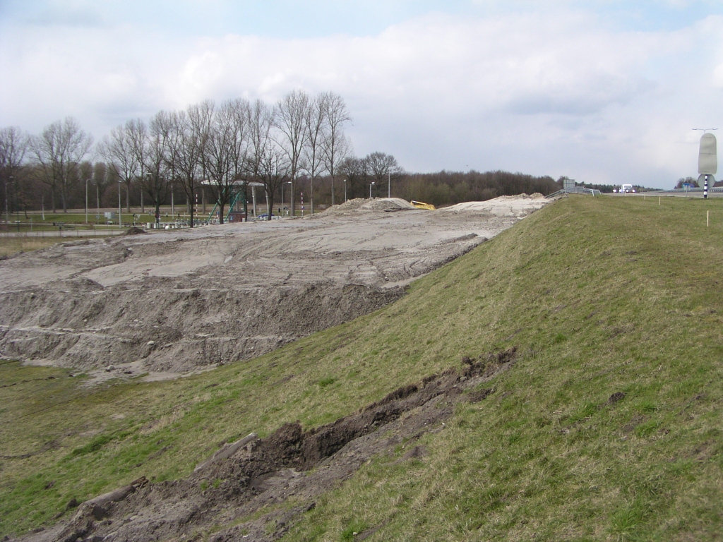 p3230003.jpg - De brug in de A50 over het Wilhelminakanaal bij Son werd reeds bemeten op 2x3 met vluchtstroken. Aan de westzijde wordt de vluchtstrook opgegeven ten behoeve van een dubbelstrooks uitvoeger naar Eindhoven-Noord en Ekkersrijt, en daar lijkt het talud al voldoende breed voor. Een goed vraag is dan ook, waarom men hier zand aan het aanbrengen is. Op de voorgrond een merkwaardige beschadiging (?) aan het talud.