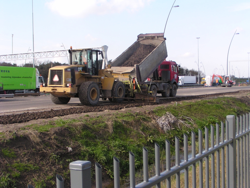 p4080059.jpg - Langs de parallelbaan bij de high tech campus heeft men een sleuf langs het asfalt gegraven, waar vervolgens een mengsel van keien en zand in wordt gestort.