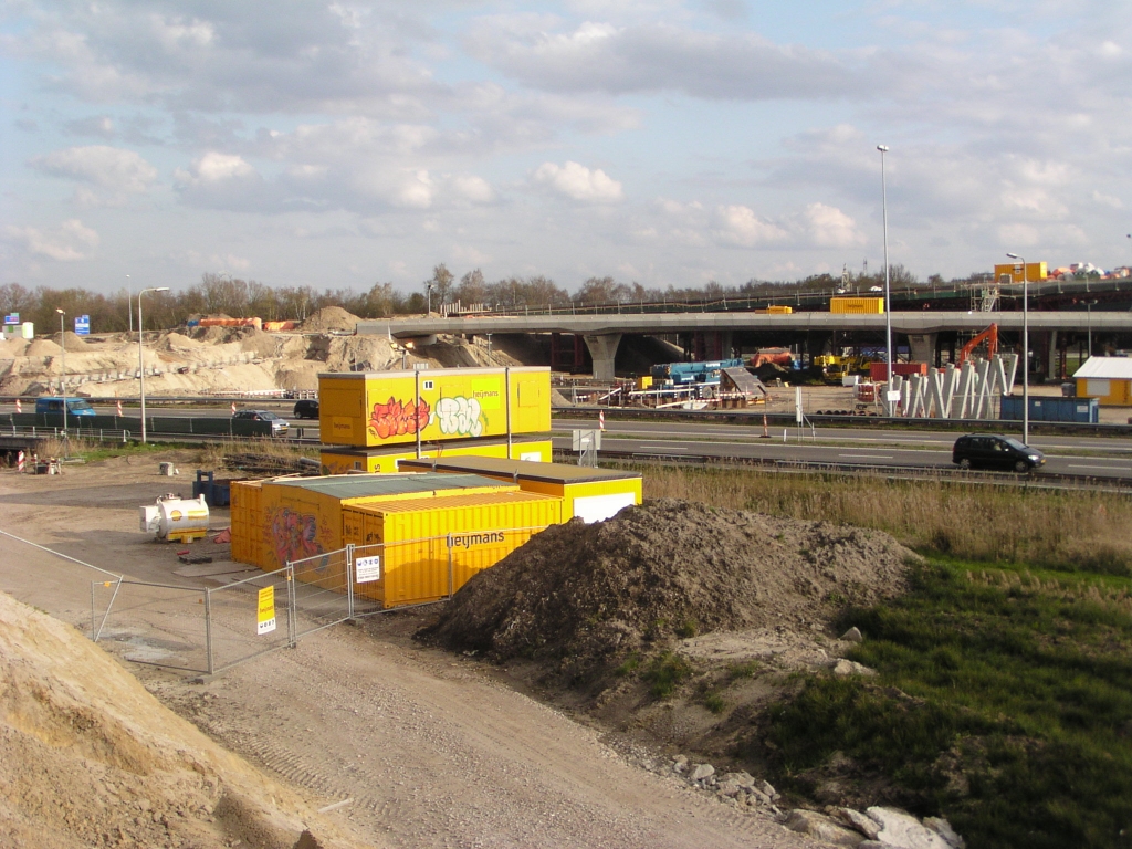 p4120160.jpg - Een poging tot in beeld brengen van KW 24, de brug over de Dommel in de A2 hoofdrijbaan, wat voorlopig bestaat uit heipalen. De palen op het landhoofd links lijken compleet, terwijl de palen rechts er zo te zien alleen nog staan voor de helft van de uiteindelijke breedte. Dat zou betekenen dat de zuidelijke hoofdrijbaanbrug (KW 24B) al kan worden gebouwd. We zien dan ook al wat damwanden in de grond waarin de funderingen voor de V-pilaren kunnen worden gestort. Als de fasering uit de vorige foto gereed is, en de oude A67 links (Venlo -> Antwerpen) in kp. de Hogt is gesloopt, en bovendien het A2 links verkeer verplaatst is naar KW 22 en bijbehorende parallelbanen, kan ook worden begonnen met KW 24A.