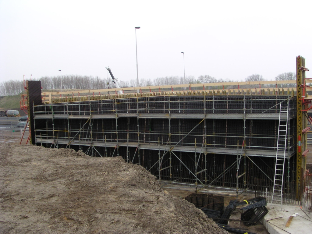 p4190102.jpg - Wapenings vlechtwerk in het noordelijk landhoofd. Aan de verkanting goed te zien dat de linker rijbaan breder is: twee rijstroken tegen eentje op de rechter. Qua omvang geeft het landhoofd een soortgelijke indruk als KW 9 (aansluiting Airport). Die draagt echter zes rijstroken en een fietspad.