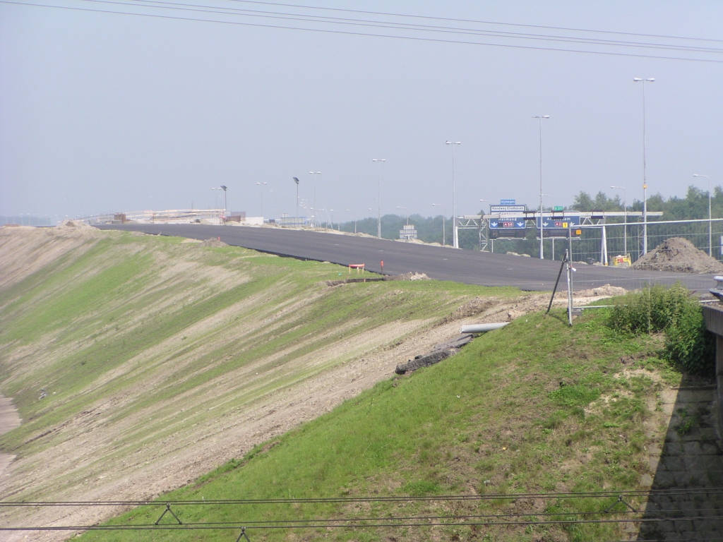 p6080034.jpg - Over KW 2 rijdende komt men hier terecht, waar verkeer vanaf de A50 komt invoegen richting KW 3 (spoorviaduct). Het naaktgeboren talud krijgt een beginnende vacht dankzij het groeizame weer.