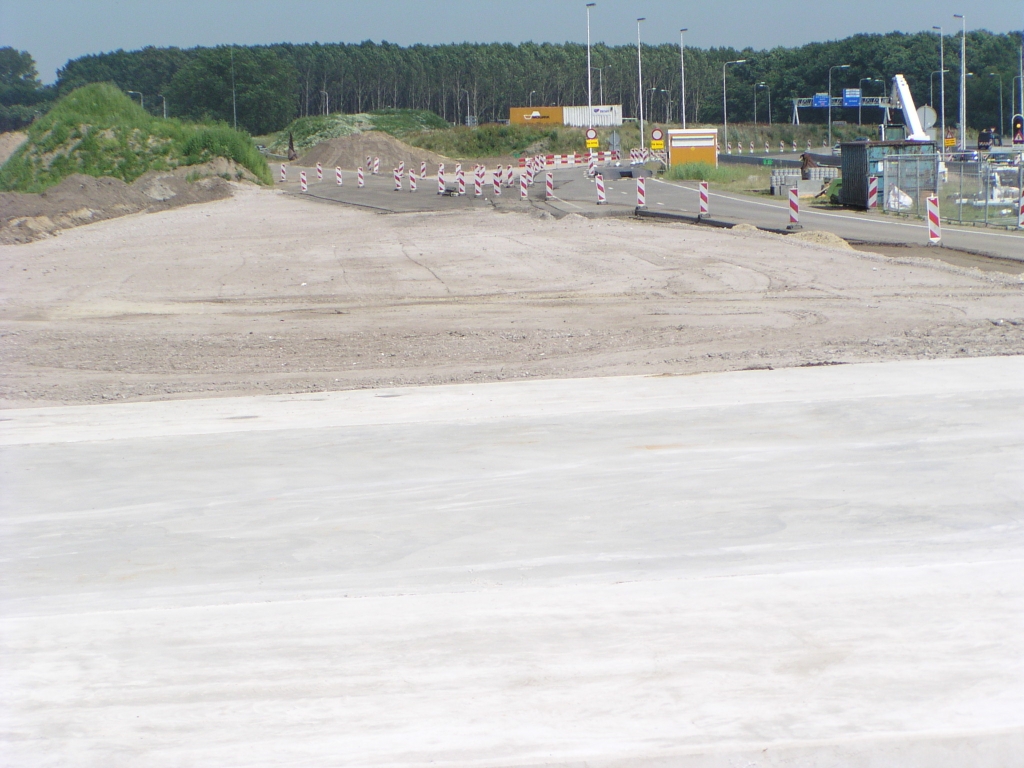 p6220121.jpg - Blik vanaf de fietstunnel over het faseringstrace met daarin A58 fragmenten van diverse ouderdom. Niets van het asfalt dat hier komt is permanent want de A50 buigt hier uiteindelijk naar links af.