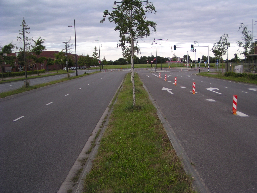 p7060061.jpg - Laten we eens gaan kijken hoe in de ontvlechtingsvariant de aansluiting Veldhoven wordt ontsloten. Dit is de Meerhovendreef, de centrale weg door de gelijknamige nieuwbouwwijk, in de richting van de aansluiting. Hij is reeds voorbereid op doortrekking. De hoofdrichting is nu nog rechtsaf, naar de Grasdreef, die aansluit op de Noord-Brabantlaan die leidt naar de aansluiting.