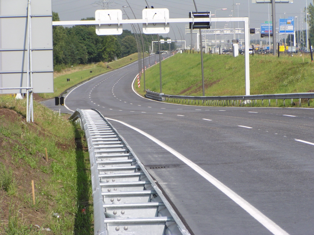 p7120039.jpg - Zelfde wegvak tegen de rijrichting in. Hier zijn maar aan 1 zijde van de weg lichtmasten geplaatst. Gezien de vormgeving van de matrixborden is dat nu juist aan de kant waar er weer een rijstrook afgaat in de uiteindelijke situatie.