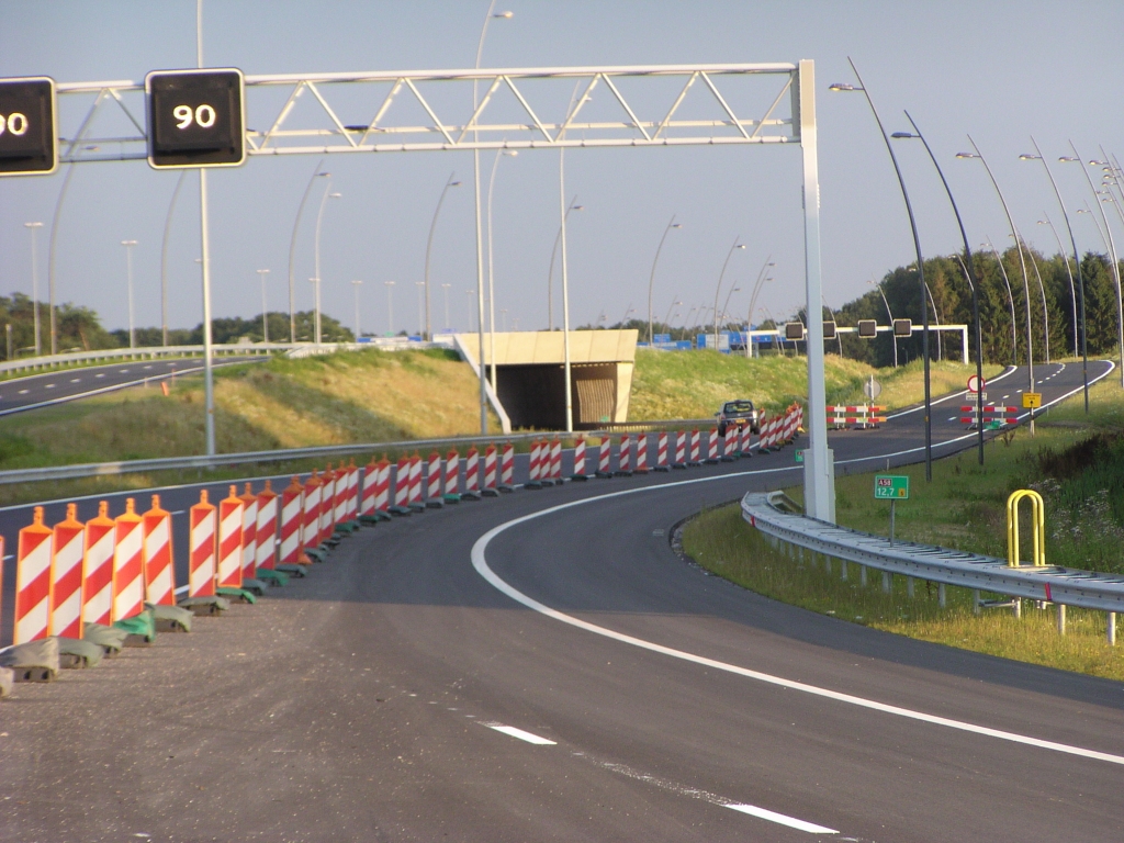 p7140044.jpg - Getuige de markeringsstippen enkele foto's eerder was men van plan de nieuwe boog simpelweg met twee rijstroken onder KW 6 door te leiden naar de oude hoofdrijbaan. Een stap verder is in plaats daarvan het verkeer rechts van KW 6 een nieuw stuk parallelbaan naar de aansluiting Airport op te sturen. Dan moet ook de parallelbaan vanaf kp. Ekkersweijer gereed zijn en over KW 6 gaan. De weg onder KW 6 zou dan vacant worden. Verderop gaan we bekijken of dit faseringsplannetje enige kans van slagen heeft.