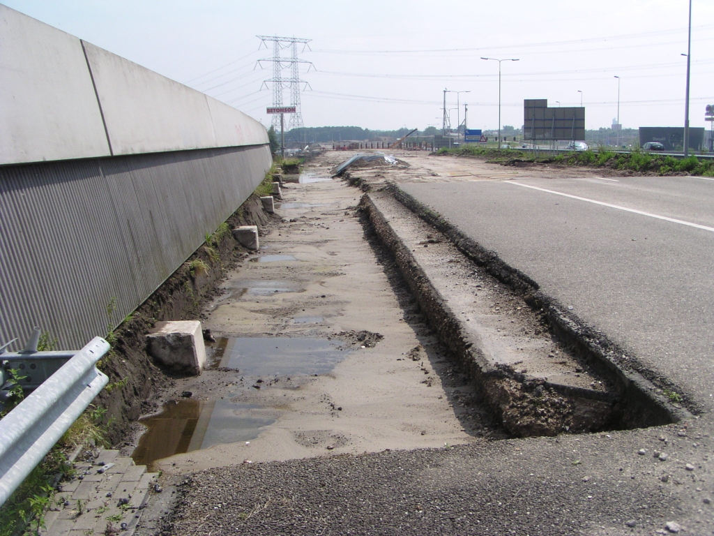 p7270009.jpg - Net ten zuiden van de Wilhelminabrug in de A50 bij Son is een stuk berm afgegraven zodat de fundering van het geluidsscherm is blootgelegd. Hier moet nieuw asfalt komen voor de tweestrooks invoeger vanuit de richting Eindhoven Woensel.