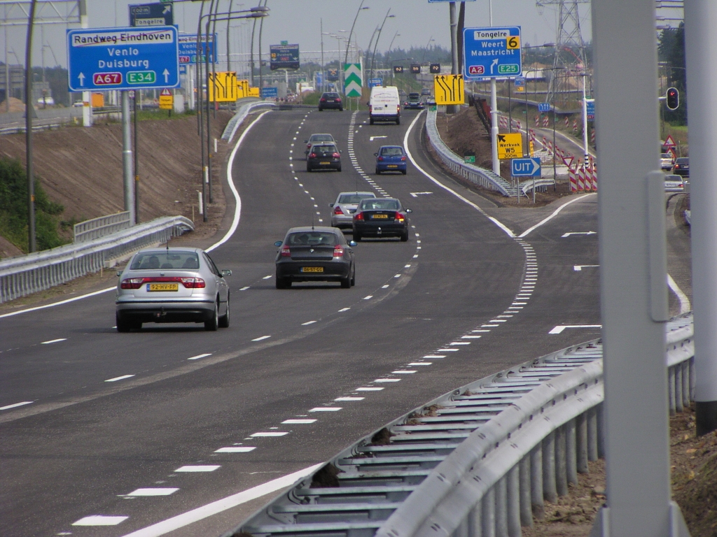 p8310078.jpg - Situatie afrit Waalre, 1 dag na openstelling. Het autoweg-type UIT bordje is de laatste permanente, de rest wat volgt is tijdelijk, ondanks de blauwe kleur. Direct na de afrit gaat de rechter rijstrook over in een uitvoeger naar het vervolg van de parallelbaan richting kp. Leenderheide, even later gevolgd door een taper voor een tweede rijstrook. Het beslismoment voor de richting Venlo versus Maastricht is ten opzichte van de oude situatie dus zo'n 800 meter eerder.