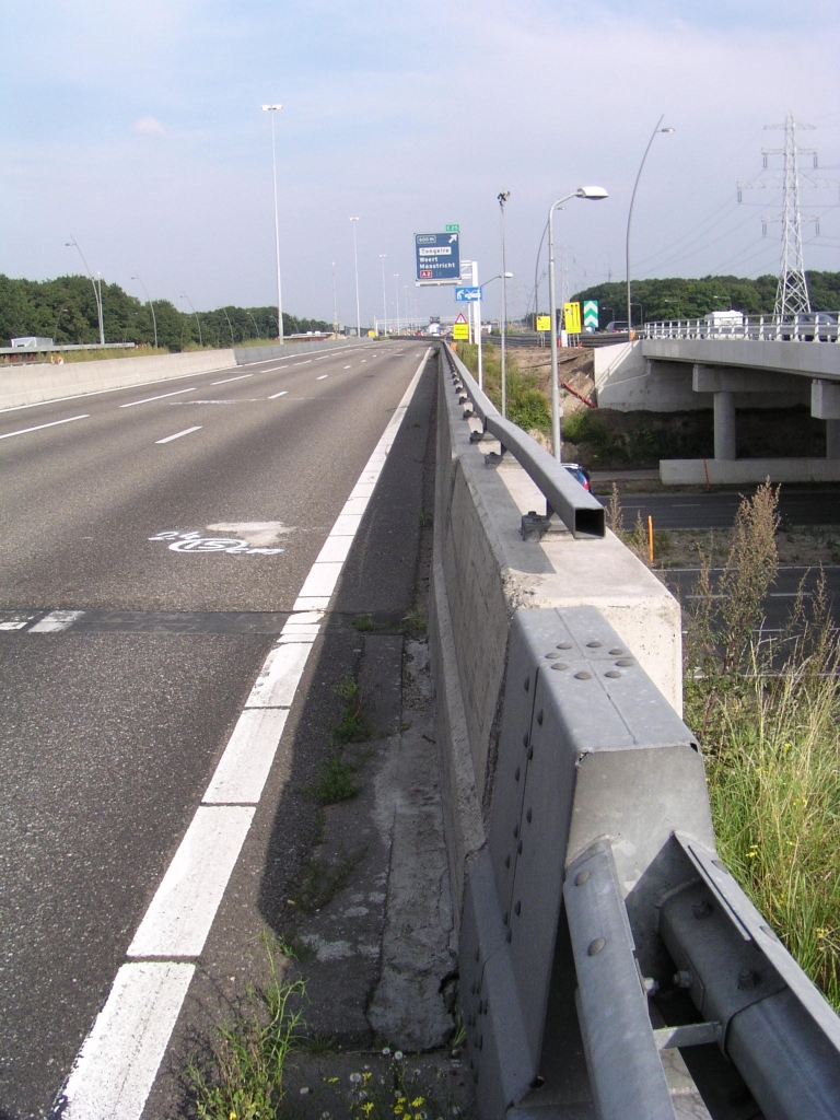 p8310098.jpg - Bij de aanleg van spitsstroken zijn diverse viaducten in de Randweg Eindhoven aangepast. We zien hier het sinds 1 dag vacante viaduct in de aansluiting Waalre. Nog in 2004 werd hier de "stoep" in het viaduct vervangen door een betonnen barrier, om de benodigde extra decimeters voor de spitsstrook te realiseren. Merk op dat de startnotitie voor de verbreding van de randweg werd gepubliceerd in 1994, en dat zonder al die tijdrovende procedures de echte verbouwing in 2004 misschien al voltooid had kunnen zijn. Kapitaalvernietiging en overlast voor het verkeer had dus vermeden kunnen worden met snellere besluitvorming.