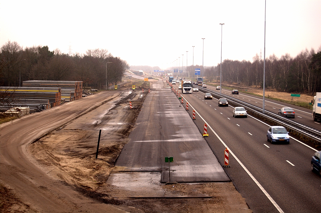 20081212-130131.jpg - Opslag van barriers en ander materiaal op het terrein van de gesloopte parkeerplaats. Nieuw asfalt voor de invoeger vanaf KW 34 doet vooralsnog dienst als ZOAB afwaterbaan.  week 200841 