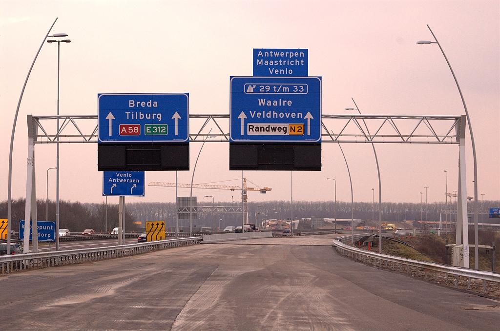 20090221-161529.jpg - Bord 5 staat vlak voor het spoorviaduct waar jarenlang drie rijstroken (2 voor de A58, 1 voor de A2) overheen hebben gelegen. Dit bord gaat daar verandering in brengen! Vier kolossale staande pijlen wijzen de weg voor A2/N2 verkeer dat moet opschuiven van links naar rechts en A58 verkeer dat precies het omgekeerde wil. Wellicht ten overvloede: in de eindsituatie wisselen deze borden van plek.