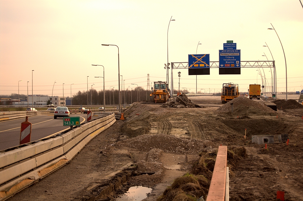 20090313-175758.jpg - Het centrum van activiteit gedurende het afsluitweekend, enige uren voor aanvang. Lastigste is uiteraard het hoogteverschil dat moet worden overbrugd bij het verleggen van de A2 rijbaan vanaf kp. Ekkersweijer naar de nieuwe rijbaan naar KW 1 toe. Vervolgens puinfundering, een aantal lagen dicht asfalt, dubbellaags ZOAB, markering, geleiderail, verlichting, hectometerbordjes, en riolering waarvan we rechts een aantal putten gereed zien liggen.