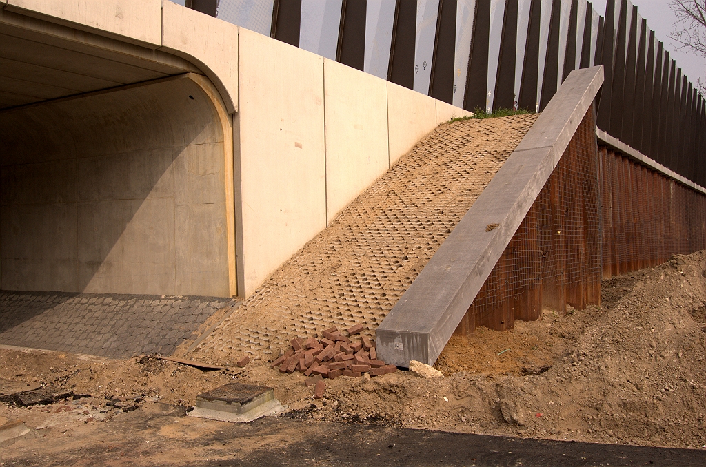 20090404-143920.jpg - We begrijpen niet zo goed waarom het taludje links met klinkerbekleding noodzakelijk is in een portaalviaduct. Grasbetontegels misschien aangebracht als loopvloer voor N2 vluchtelingen die hun weg hadden gevonden tussen de geluidsschermen. Als derde afrondende activiteit is traliewerk aangebracht op de damwanden voor klimplanten.