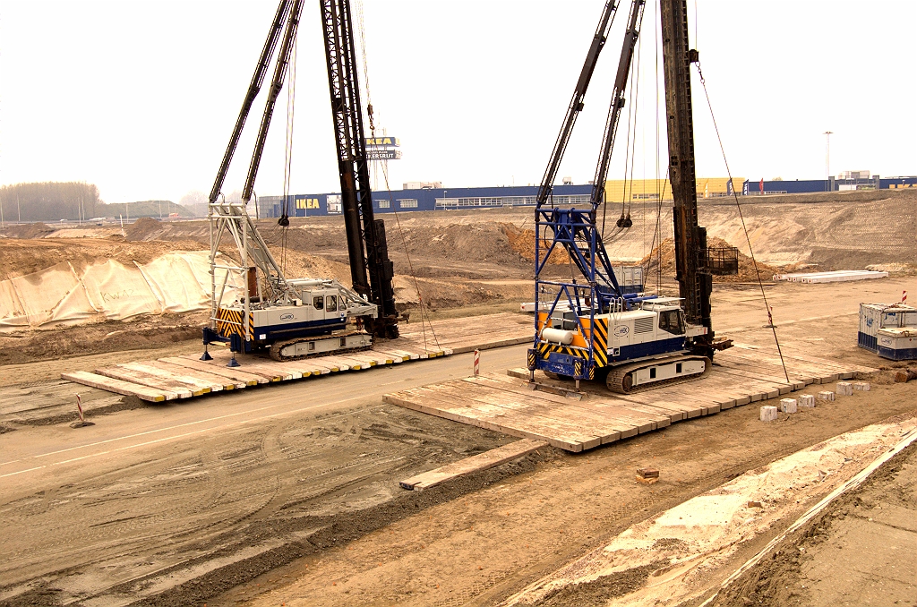 20090412-145917.jpg - Twee heimachines zijn ingezet voor de fundering van de landhoofden van het viaduct in de A50 over de verbindingsweg Nijmegen-Woensel. Voor de werken is geen asfalt opgebroken van de slingerfasering, die vier rijstroken breed was, terwijl de uiteindelijke verbindingsweg maar twee rijstroken zal hebben zonder vluchtstrook.