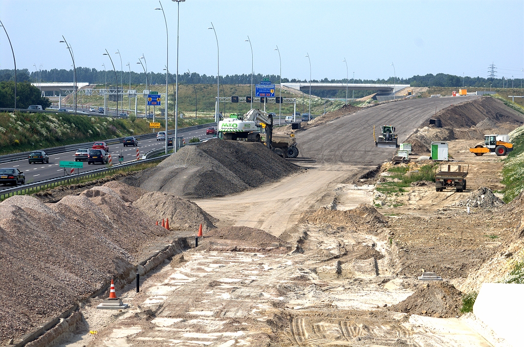 20090627-164337.bmp - Grondverzet in het talud naar KW 5 lijkt gereed. De parallelrijbaan komt met twee rijstroken vanonder KW 7 (onder), zodat er een kort stukje vierstrooks rijbaan ontstaat. Op het talud naar KW 5 verdwijnt rijstrook 3 middels een taper. De versmalling naar twee rijstroken is pas na KW 4B (middenboven in de foto).