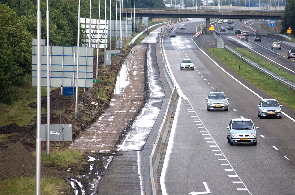 20090712-165836.bmp - Verbreding van de (nog) A58 tussen het viaduct Huizingalaan en het fietsviaduct Achtse Barrier-Aquabest. Doel daarvan lijkt duidelijk: een doorlopende weefstrook tussen de toerit Ekkersrijt in de richting Tilburg, en de verbindingsweg Nijmegen-Amsterdam in het knooppunt Ekkersweijer. Maar het verbreedsel zet zich voort langs de bestaande uitvoeger naar de A2, althans over een klein stukje. Ligt er een verdubbeling van de verbindingsweg in het verschiet?