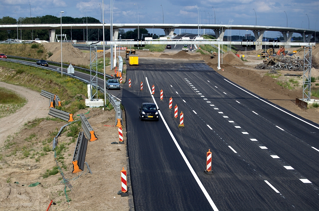 20090718-175415.bmp - Vierdaagse van de Hogt, dag 2. Resten van het oude viaduct volledig verwijderd, althans op de plek waar de nieuwe verbindingsweg moet komen. Het resultaat van de afsluiting afgelopen nacht van de oude verbindingsweg Amsterdam-Antwerpen mag er ook zijn. Een volledig gerealiseerde nieuwe rijbaan voor het invoegen van het verkeer uit de richting Amsterdam op de A67 naar Antwerpen. Inclusief ZOAB en thermoplast markering. Begin van de taper zichtbaar.