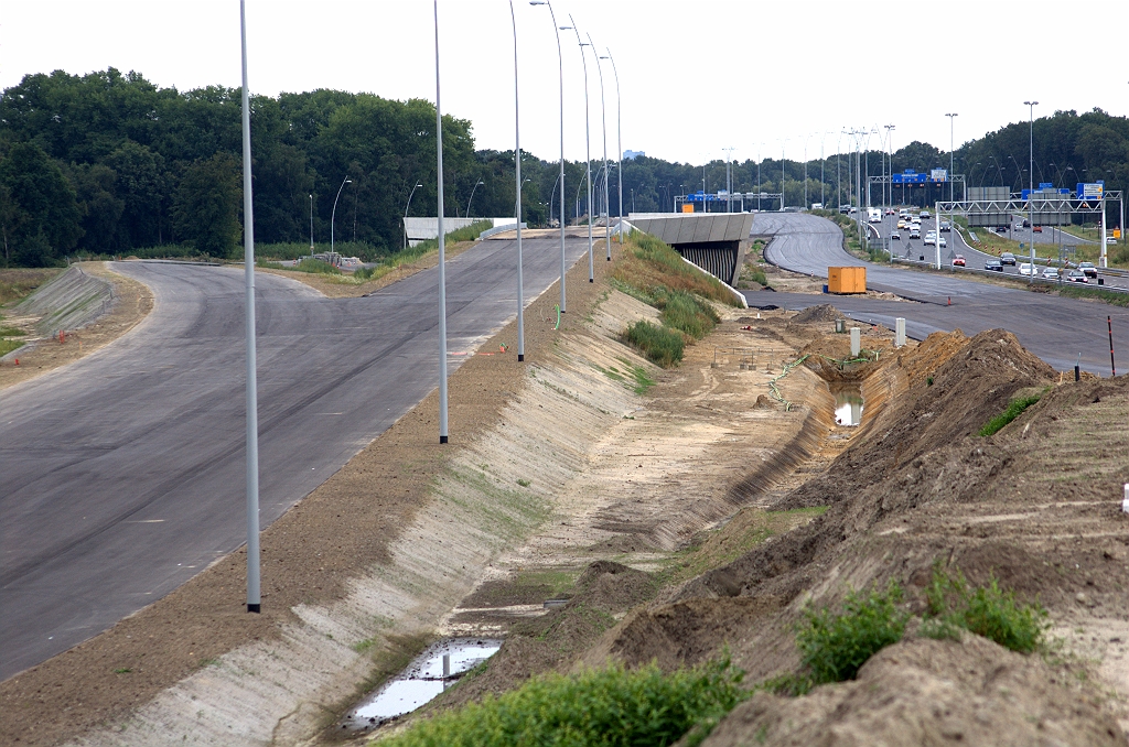 20090809-170823.bmp - Verlichting geplaatst langs de A2 hoofdrijbaan ten noorden van KW 7, foto genomen tegen de rijrichting. Vlak afgewerkte bermen langs deze rijbaan, en de invoegende parallelrijbaan, zijn een indicatie dat er alleen nog maar ZOAB op hoeft. Situatie vanaf 28 september: verkeer links naast KW 7, maar nog niet erover.  week 200928 