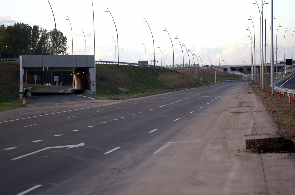 20091004-184055.bmp - KW 6 is vorig jaar vijf maanden in gebruik geweest om het verkeer uit de richting Tilburg vanaf de nieuwe verbindingsweg onder KW 4A naar de oude hoofdrijbaan te leiden. Sinds de openstelling van de parallelrijbaan naar de aansluiting Airport in augustus 2008 ligt de onderdoorgang er weer werkloos bij. Nu de hoofdrijbaan zijn definitieve verschijning krijgt kan ook het enkelstrooks rijbaantje onder KW 6 worden afgemaakt.