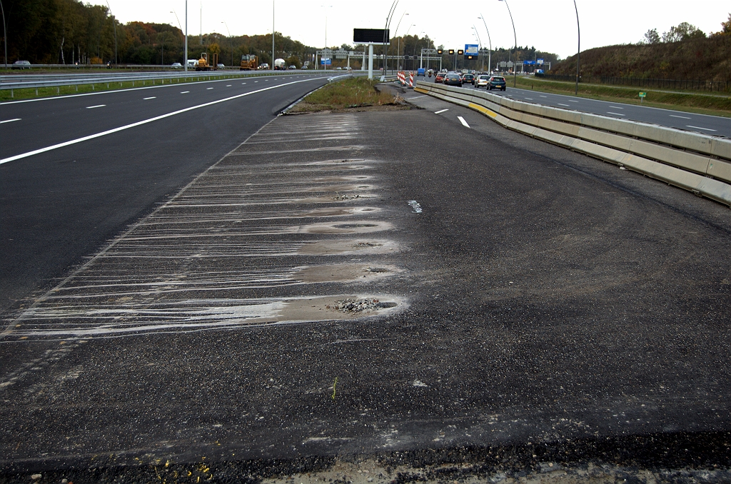 20091025-145321.bmp - Een paar honderd meter zuidelijker de logischer lijkende locatie van de volgende CADO, tussen oostelijke hoofd- en parallelrijbaan. Cylinders asfalt verwijderd, als ware het proefboringen, voor de geleiderailstaanders.