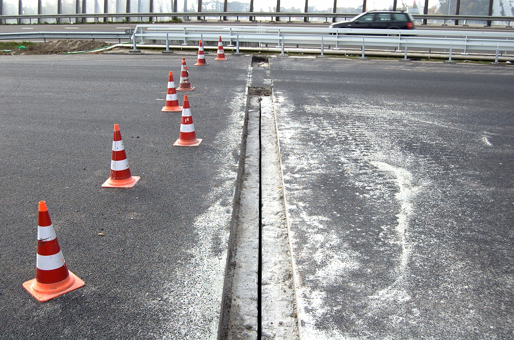 20091025-152605.bmp - Evenals in KW 12 is het werk op het westelijk viaduct nog bezig. Dezelfde werkwijze als we eerder zagen in KW 3. Eerst oude voegovergang en asfalt verwijderen, dan over de "lege" overgang asfalteren, inclusief ZOAB, dan een strook asfalt weer verwijderen en de nieuwe overgang monteren.