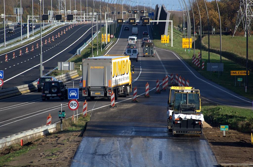 20091114-152654.bmp - In de overgang tussen nieuw en bestaand parallelrijbaantrace moet een overgang komen tussen ZOAB en dicht asfalt. Vermoedelijk is het stukje asfalt tussen de walsen en geleidebakens dus een afritje dat enige centimeters hoogteverschil moet overbruggen.