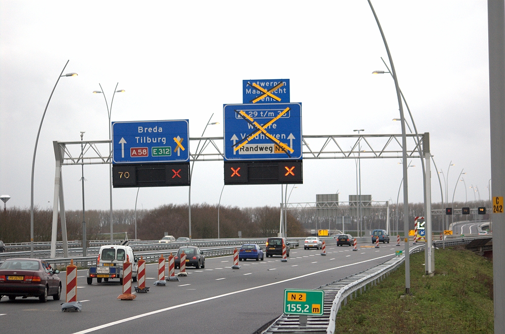 20091206-144948.bmp - Bij KW 3 komen de verkeersstromen samen vanuit de richtingen Amsterdam en Nijmegen, met elk 1 rijstrook. Na een kort ritsvakje versmalt ook die samenvoeging tot een enkelstrooks verbindingsweg in de richting Breda in kp. Batadorp. Verbouwing aan de borden bleef beperkt tot afplakken/magneten plaatsen.  week 200911 