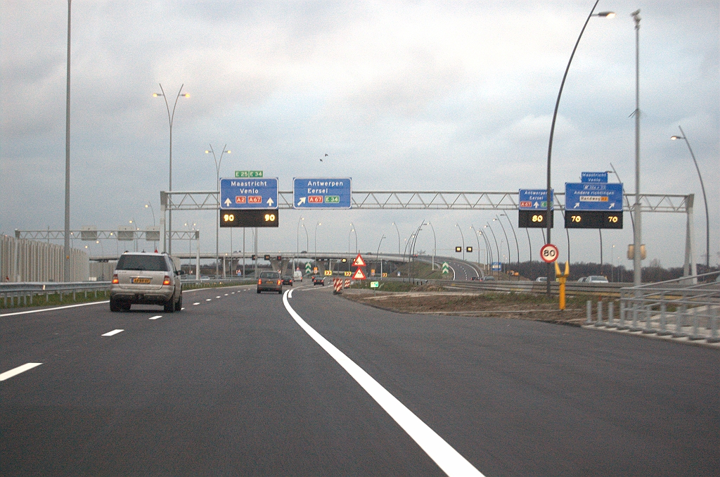 20091212-170000.bmp - Zo raken we ons weer bewust van de parallelrijbaan, in eerste instantie omdat er hier uitwisseling plaats vindt van verkeer. Het portaal dat beide rijbanen overspant benadrukt dat nog eens. Het grote contrast met de "Poot van Metz", waar de parallelrijbaan als onbeduidende stadsweg werd weggestopt, wordt veroorzaakt door KW 19. Hier is de N2 opeens de hoofdrolspeler.