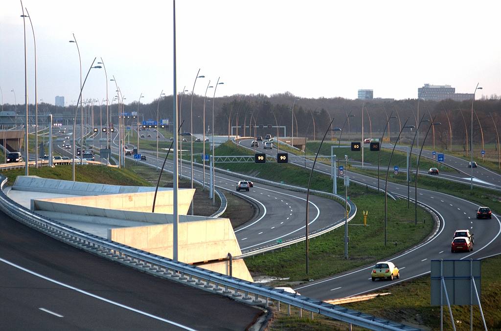 20091213-170331.bmp - Hoofd- en parallelrijbaan zij aan zij vanonder KW 5. Typerende uitvoeringsverschillen zoals vluchtstrook versus pechhaven en verschillende modellen lichtmast en signaleringsportaal.