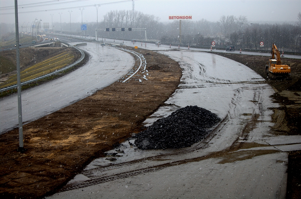 20100124-150613.bmp - Sneeuwdek is weliswaar verdwenen in Ekkersrijt, maar nieuwe witte vlokken dalen al weer neer. Onze helden gaan ondertussen onverschrokken door. Oostelijke (rechtse) A50 rijbaan volledig ontdaan van de resten van de col d'Ekkersijt die erop heeft gelegen. Toch is men als eerste in de westelijke rijbaan van start gegaan met het plaatsen van geleiderail.  week 201002 