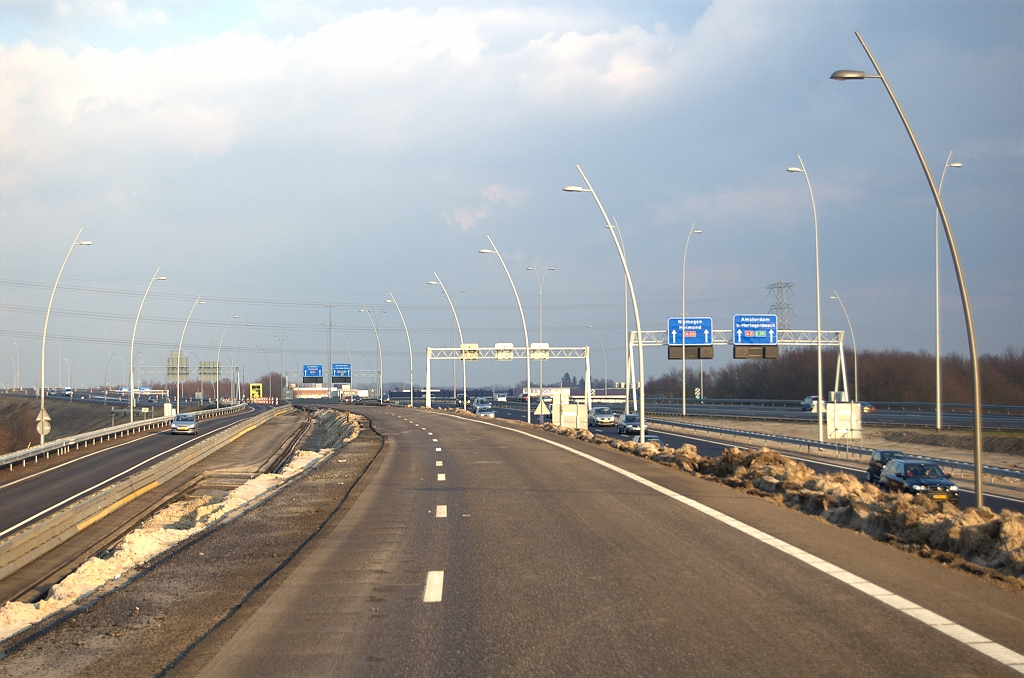 20100220-173553.bmp - En hoe gaat het nu verder met het knooppunt Batadorp? Als de nu verlaten A58 rijbaan (standpunt) is gesloopt, kan de nieuwe rijbaan links worden verbreed naar vier rijstroken, waarvan er twee afvallen naar de parallelrijbaan in zuidelijke (rechtse) richting. De lichtmasten voor die definitieve situatie zijn al geplaatst, en rechts zien we de overgang van lichte naar donkere kleur, zodat daar de autoweg N2 zal beginnen.