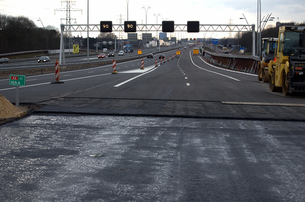 20100221-170217.bmp - Aangekomen bij de A2 zien we dat er van de dunne toplaag van het tweelaags ZOAB weer een strookje is weggefreesd. Wellicht is zo'n overlappende constructie steviger. Geleiderail in onderdelen neergelegd waar het nog moet worden aangebracht langs het damwanden geluidsschermpje.  week 201005 