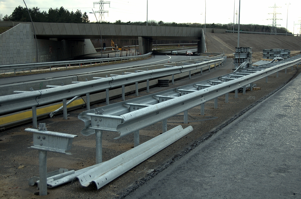 20100221-171022.bmp - Oversteekasfalt dat eerder werd gebruikt voor faseringen blijft dus liggen. Voor het plaatsen van de geleiderailsteunen zijn aldus een boel gaten geboord.