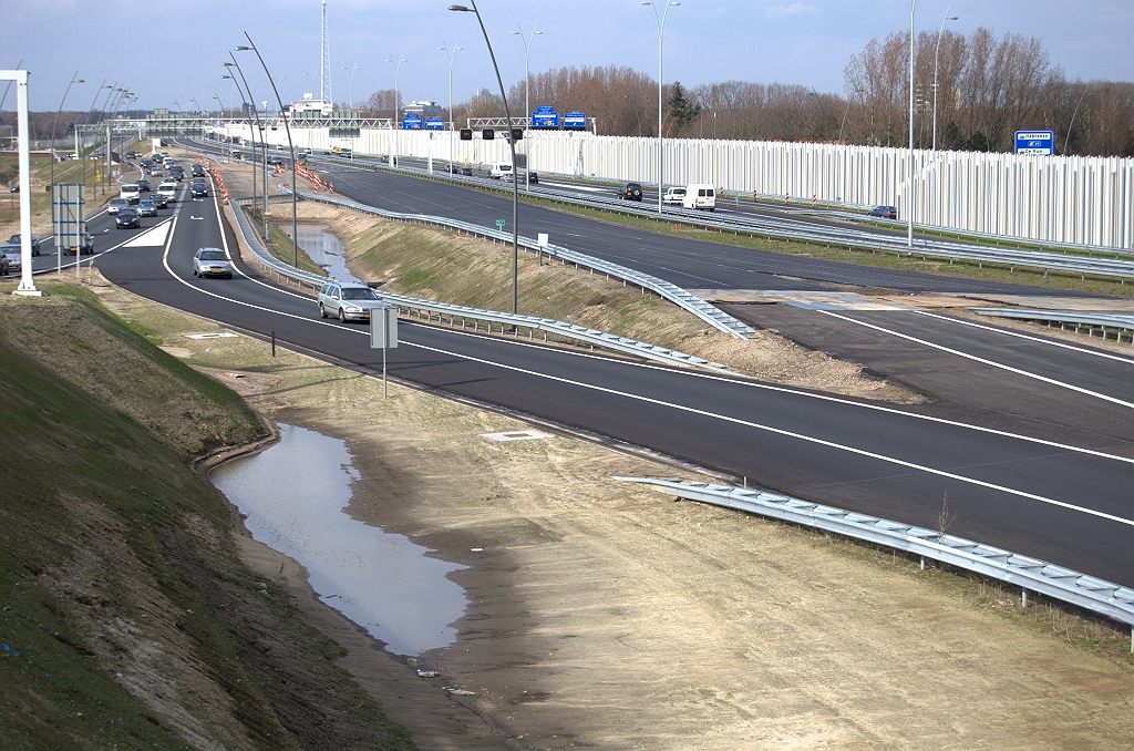 20100327-164457.bmp - Twee wegvakjes in de A2 hoofdrijbaan in zuidelijke richting waren nog niet voorzien van dubbellaags ZOAB. Hier de eerste, vlak ten noorden van het knooppunt de Hogt. In de weekendafsluiting van 26-28 maart 2010 wordt het doorgaande verkeer omgeleid over de parallelrijbaan. Op de zaterdagmiddag is zo te zien de eerste grofkorrelige laag al gereed.