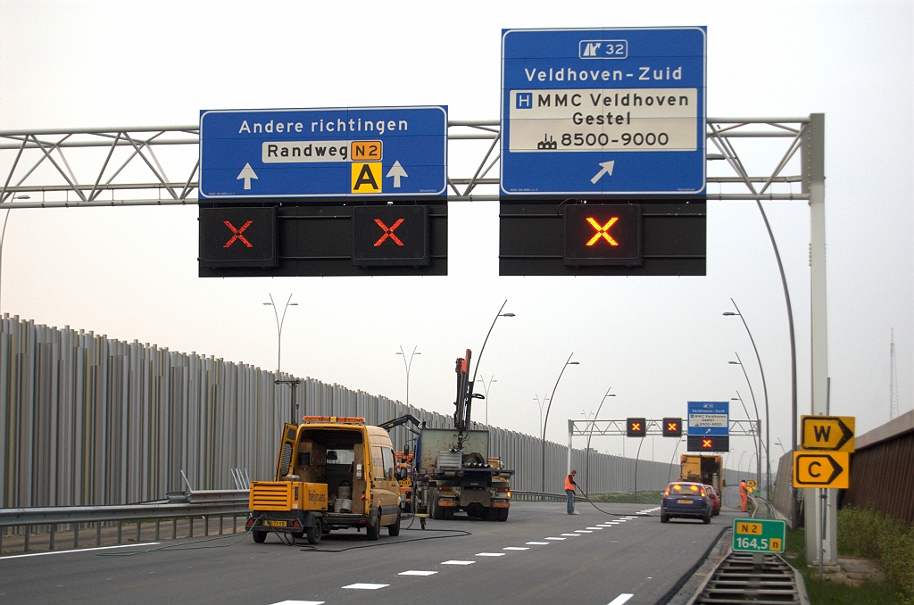 20100425-201456.bmp - De gebruikelijke wijzigingen zoals het verdwijnen van de Randweg Eindhoven en het nieuwe afritsymbooltje. Daarnaast het schrappen van de vooraankondiging van de volgende afrit (Veldhoven) en het verschijnen van bedrijvennummering. De gele bordjes staan nabij een vluchtdeur in het geluidsscherm, maar daar zijn geen sanitaire voorzieningen.  week 200905 