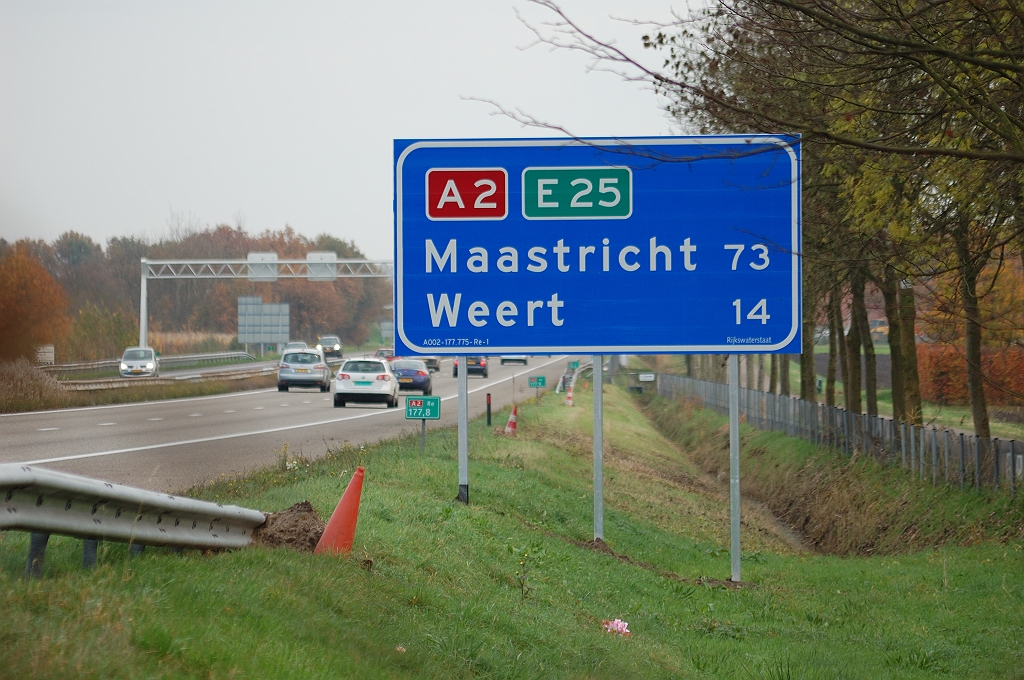 20101106-163902.bmp -  Oude afstandenbord  stond, zoals in de oude stijl gebruikelijk, op 300 meter vóór de afrit. Thans staat het nieuwe bord twee kilometer zuidelijker, ná de toerit. Tevens blijkt de NBA methodiek uit het omdraaien van de volgorde, zodat het verste doel nu bovenaan staat.