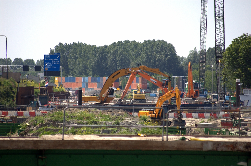 20100626-143016.bmp - Chaotisch aandoend bouwterrein waar de verdiepte A4 HRR gerealiseerd moet worden, ingeklemd tussen de oude rijbanen links en de kom van Leiderdorp rechts. Hier vindt de verbreding aan de westkant plaats, terwijl hij vanaf de aansluiting Hoogmade tot hier aan de oostkant komt te liggen. Opgestapelde containers lijken een geimproviseerd geluidsscherm te zijn.