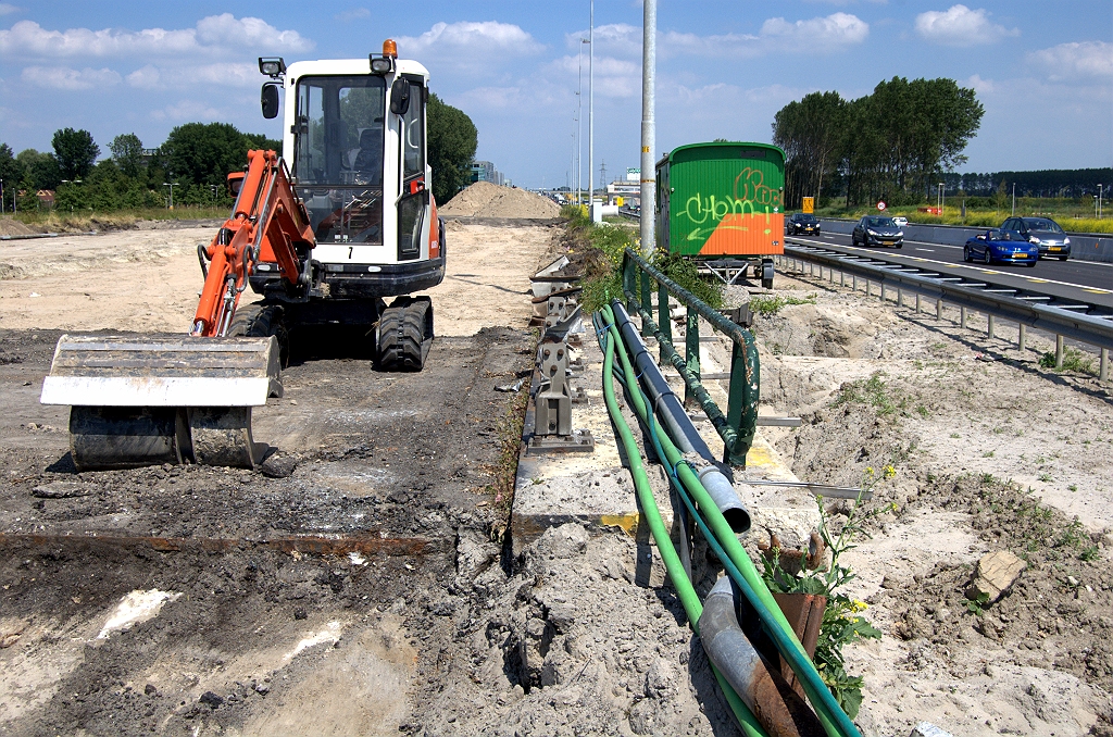 20100626-150013.bmp - In de toelichting op het tracébesluit is de volgende passage te vinden: "Ten noorden van de Ericalaan/ Mauritssingel wordt het lengteprofiel uit kostenoverwegingen hoger gelegd dan de huidige situatie vóór verbreding tot maximaal +2,75 N.A.P.". De nieuwe rijbaan rechts waarover thans al het verkeer rijdt ligt dus ook op hoogte. Een wilde gok is dat op deze manier dure grondkeringsmaatregelen worden voorkomen tijdens de faseringen.